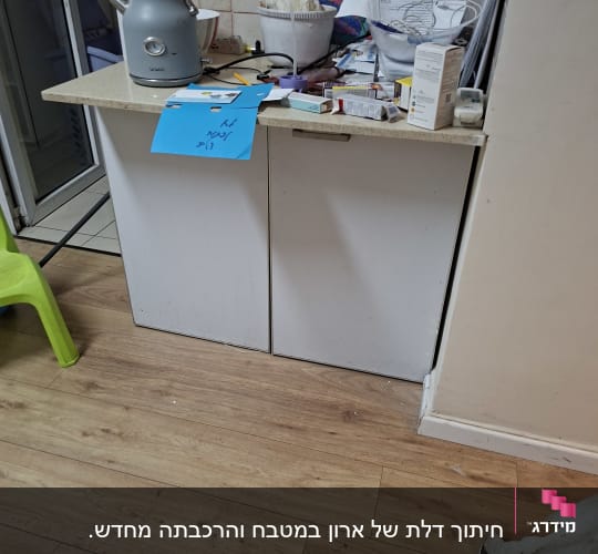 מטבח עם קומקום, כיסא ירוק, ומוצרים שונים על השיש